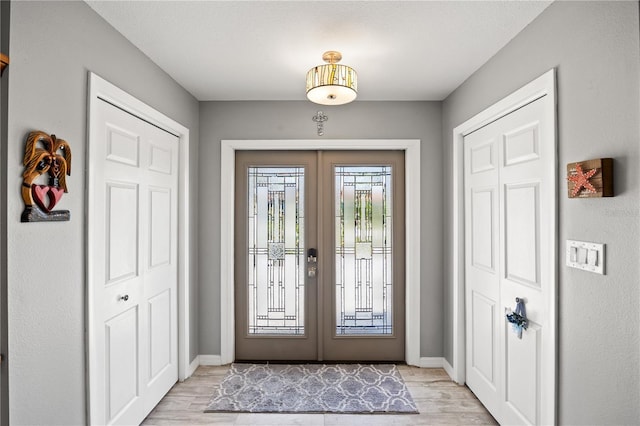 entryway featuring french doors, light wood-style flooring, and baseboards