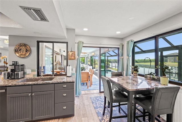 dining area with a textured ceiling, light wood-style flooring, recessed lighting, a water view, and visible vents