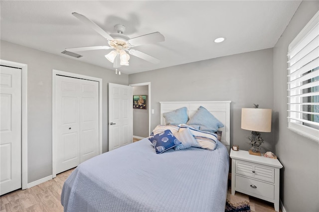 bedroom with ceiling fan, light wood-style flooring, visible vents, and baseboards