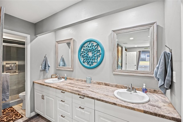 full bathroom featuring a sink, a shower stall, toilet, and double vanity