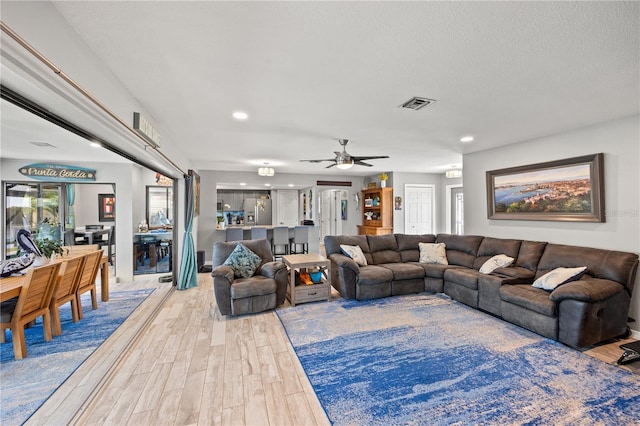 living area featuring a textured ceiling, wood finished floors, visible vents, and recessed lighting