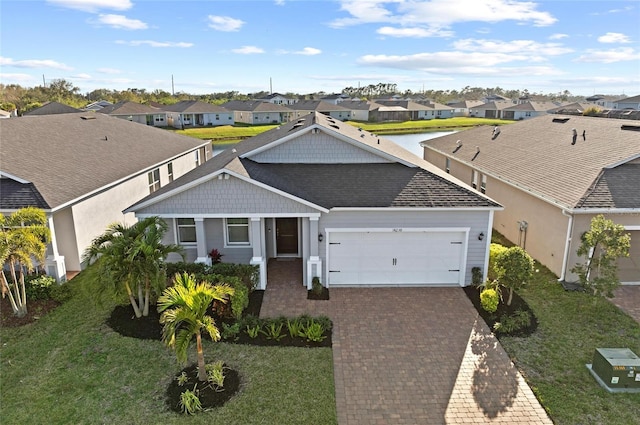 view of front of house with a garage, decorative driveway, a front yard, and a residential view