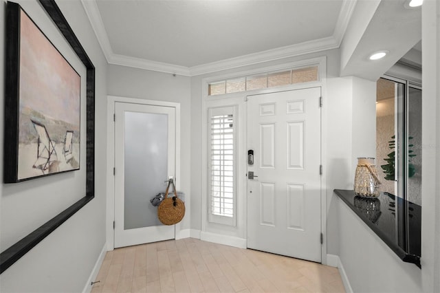 entrance foyer featuring ornamental molding, light wood-style flooring, and baseboards