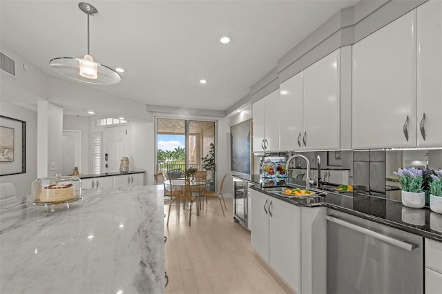 kitchen with pendant lighting, white cabinetry, a sink, dark stone countertops, and dishwasher