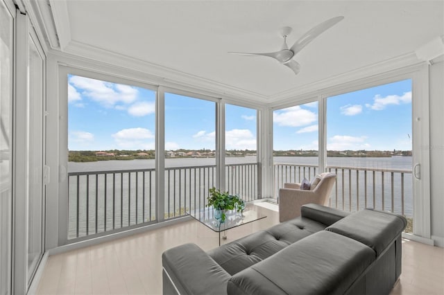 sunroom with ceiling fan and a water view