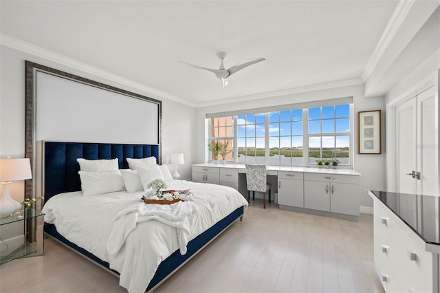 bedroom featuring light wood-style floors, ceiling fan, ornamental molding, and built in study area