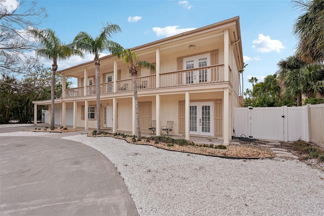 view of front of home with french doors, a gate, a balcony, and stucco siding