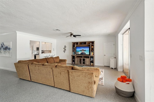 living area with a textured ceiling, baseboards, visible vents, and crown molding