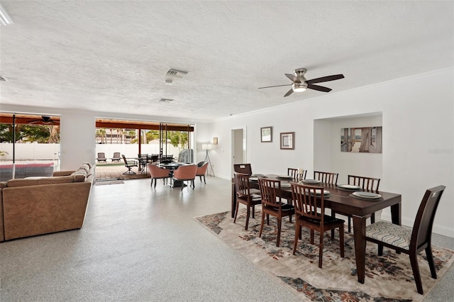 dining space with a textured ceiling, ceiling fan, speckled floor, visible vents, and ornamental molding