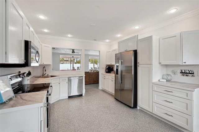 kitchen with a sink, white cabinets, light countertops, appliances with stainless steel finishes, and crown molding