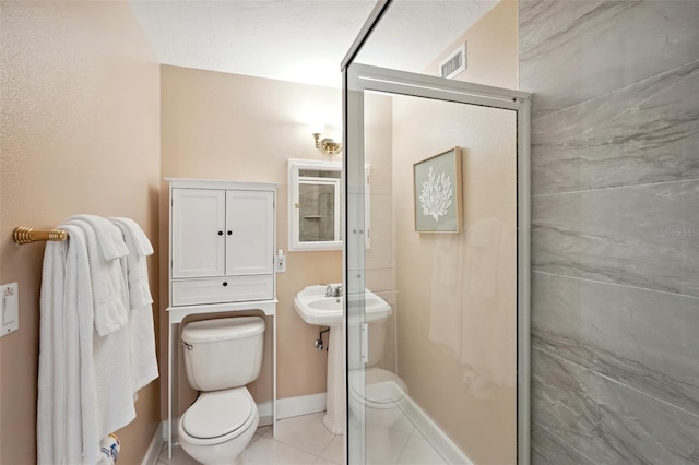 bathroom featuring tile patterned flooring, toilet, visible vents, baseboards, and a stall shower