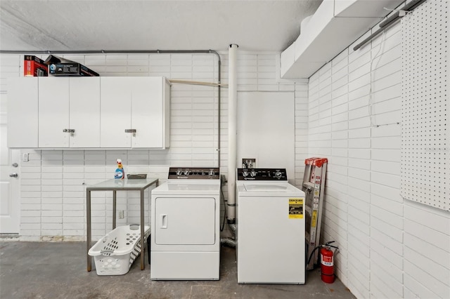 laundry area with tile walls, cabinet space, and washer and clothes dryer