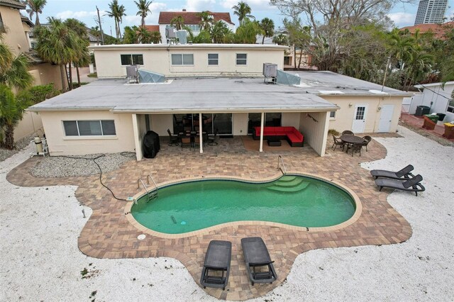 back of house featuring outdoor lounge area, stucco siding, a patio area, and an outdoor pool