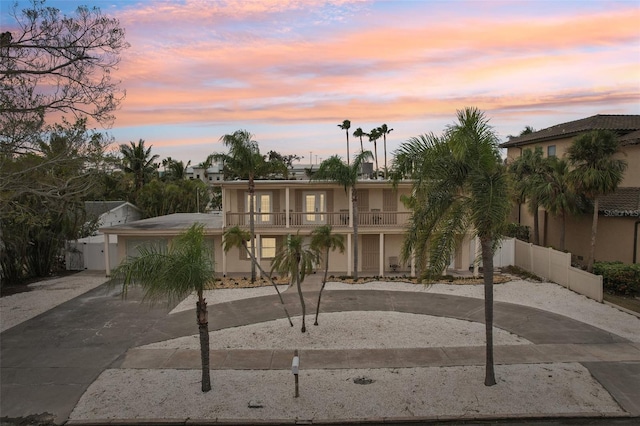 view of front facade featuring aphalt driveway, a balcony, and stucco siding