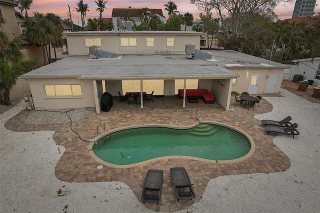 rear view of property featuring a patio area, an outdoor pool, and stucco siding