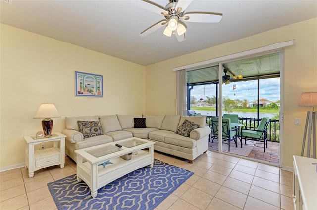 living room with a water view, ceiling fan, baseboards, and light tile patterned flooring