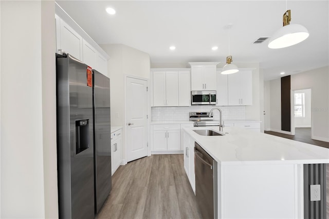 kitchen featuring stainless steel appliances, a sink, white cabinets, and pendant lighting