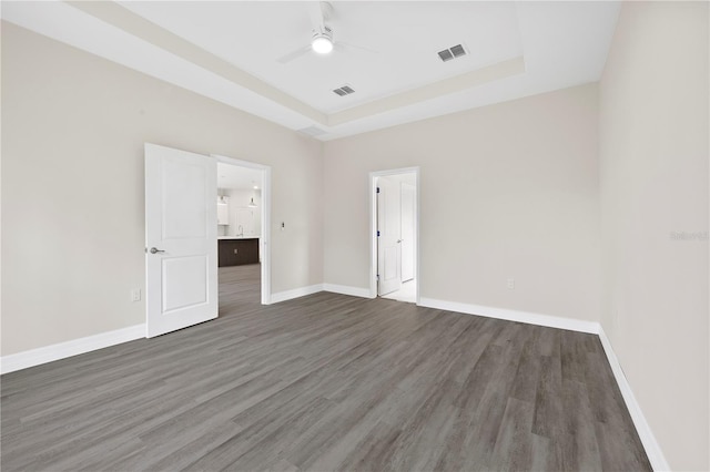 empty room featuring baseboards, visible vents, and a raised ceiling