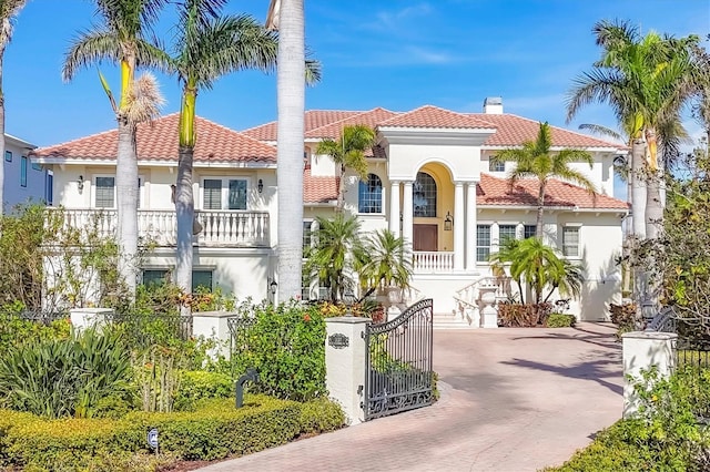 mediterranean / spanish house featuring driveway, a balcony, a tiled roof, and stucco siding