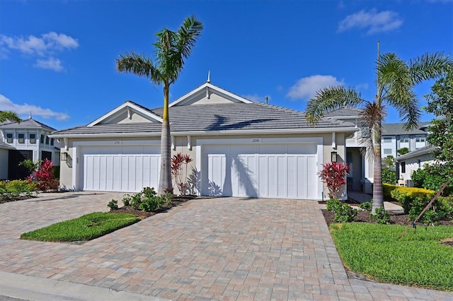 ranch-style house featuring an attached garage, decorative driveway, and stucco siding