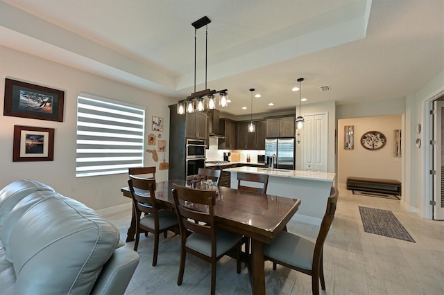 dining room featuring baseboards, visible vents, a raised ceiling, light wood-style floors, and recessed lighting