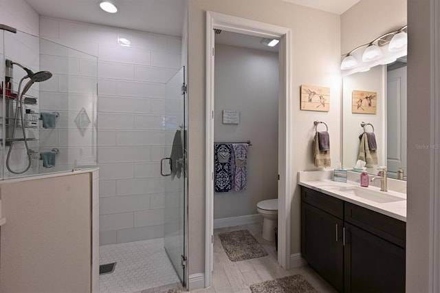 full bathroom featuring a stall shower, baseboards, vanity, and toilet