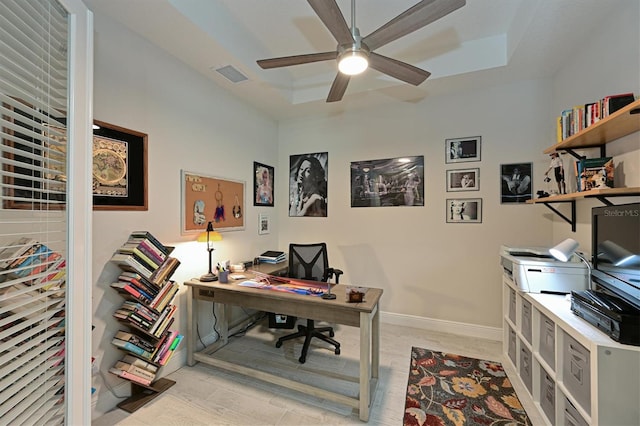 office area featuring baseboards, visible vents, a raised ceiling, ceiling fan, and light wood-style floors