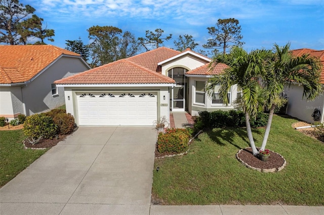 mediterranean / spanish home featuring stucco siding, concrete driveway, an attached garage, a tiled roof, and a front lawn