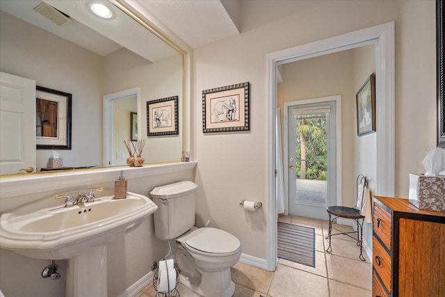 half bath featuring baseboards, visible vents, toilet, tile patterned floors, and a sink