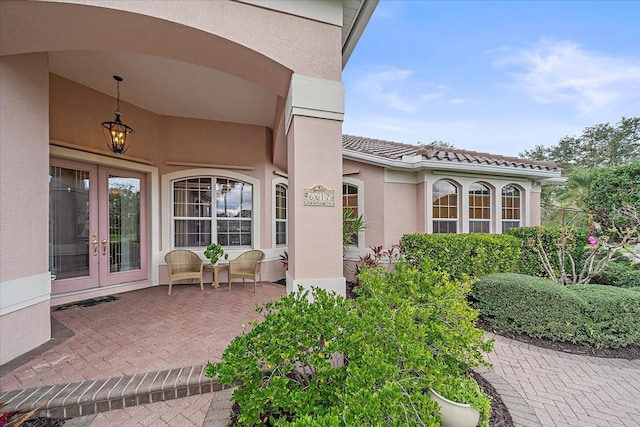 entrance to property with french doors, a tiled roof, and stucco siding