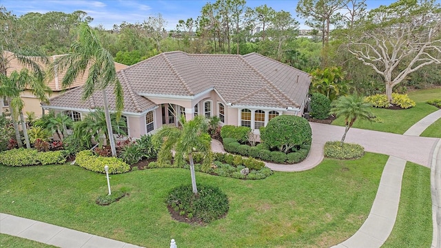 view of front of property with driveway, stucco siding, a tile roof, and a front yard