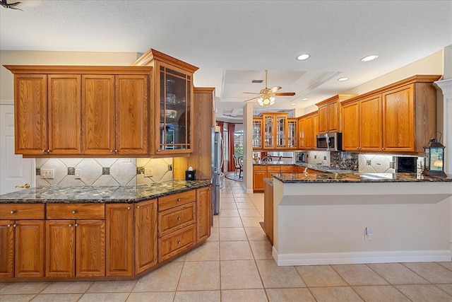 6617 Nautical Dr, Lakewood Ranch, FL 34202 - kitchen with stainless steel appliances, dark stone counters, and brown cabinetry