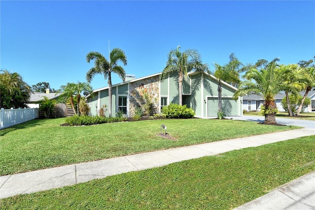 mid-century home featuring an attached garage, fence, and a front yard