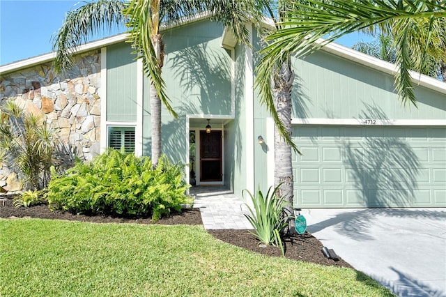doorway to property with concrete driveway, a yard, and a garage