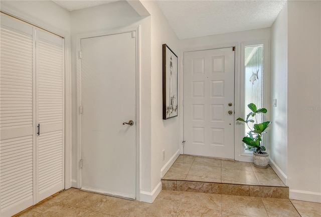 entryway with light tile patterned flooring and baseboards