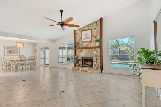 living room with light tile patterned floors, high vaulted ceiling, a stone fireplace, and ceiling fan