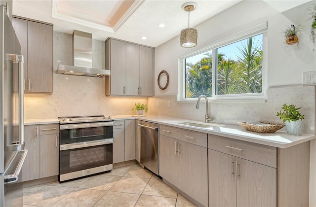 kitchen featuring light countertops, stainless steel appliances, a sink, and wall chimney exhaust hood