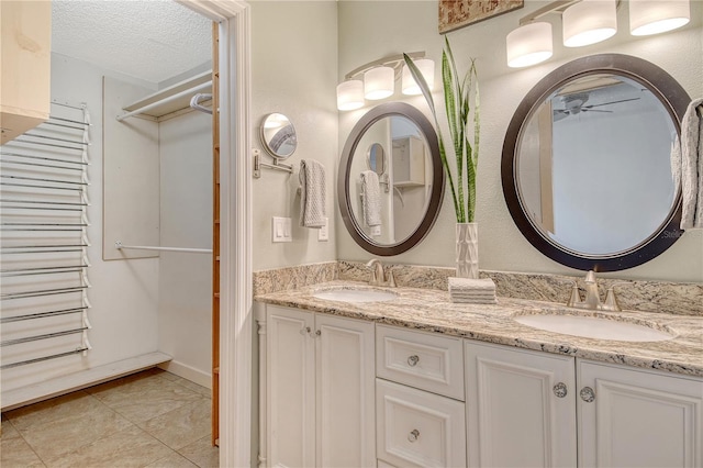 full bathroom with double vanity, a ceiling fan, tile patterned floors, and a sink