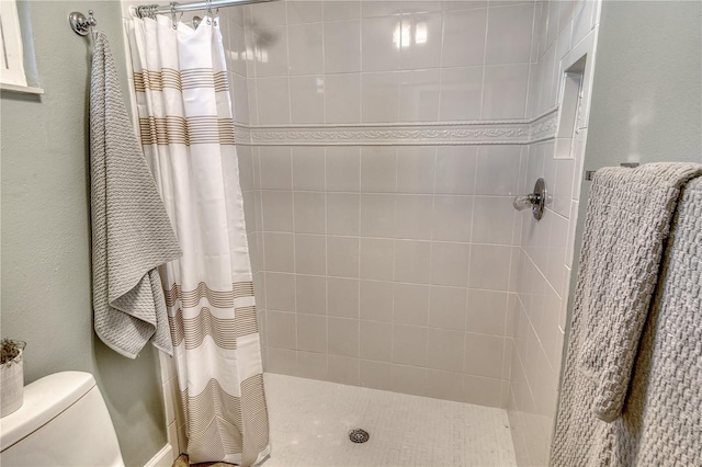 full bathroom featuring a tile shower and toilet
