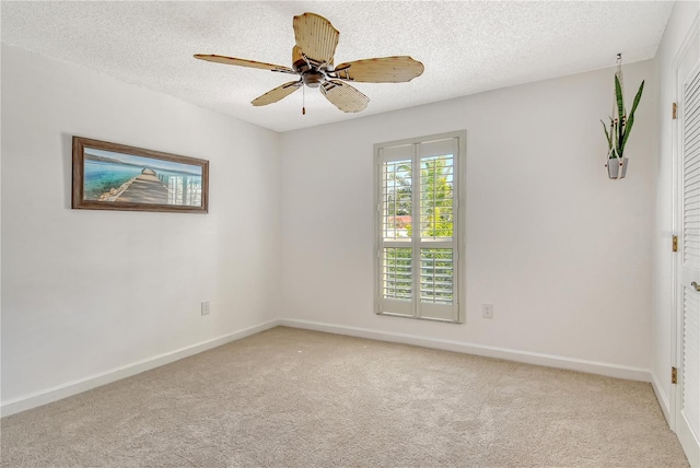 carpeted spare room with baseboards, a textured ceiling, and ceiling fan