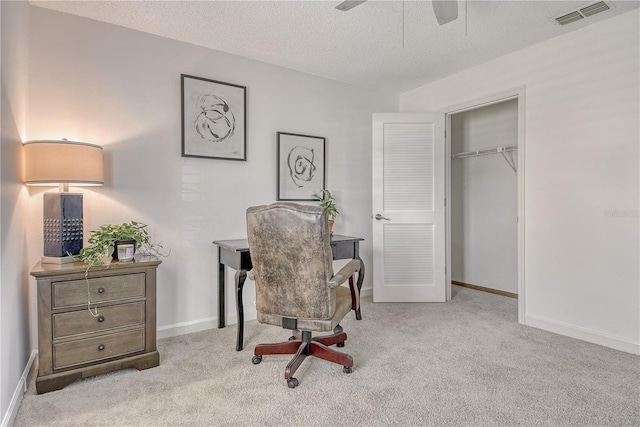 office area featuring a ceiling fan, a textured ceiling, visible vents, and carpet