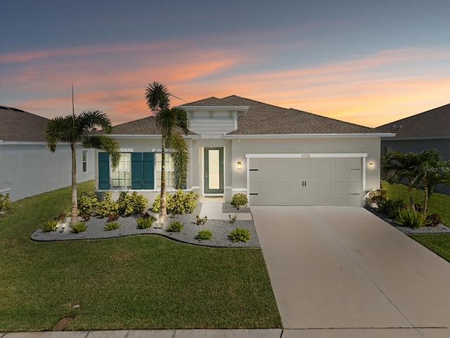 view of front of property featuring concrete driveway, a lawn, an attached garage, and stucco siding