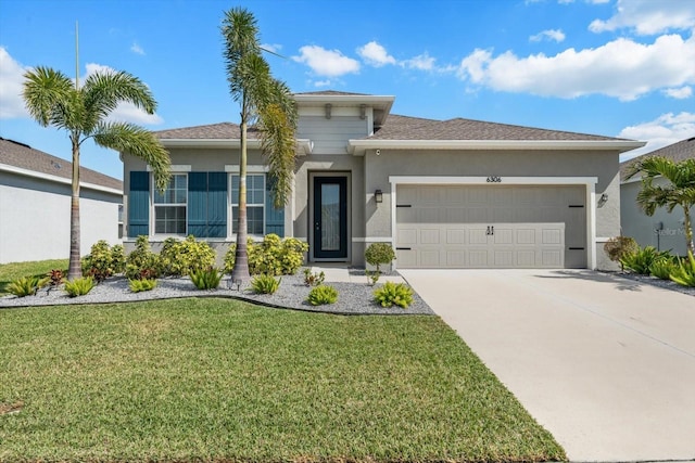 prairie-style home with a front lawn, concrete driveway, an attached garage, and stucco siding