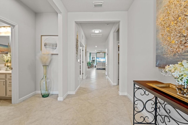 corridor featuring light tile patterned floors, baseboards, and visible vents