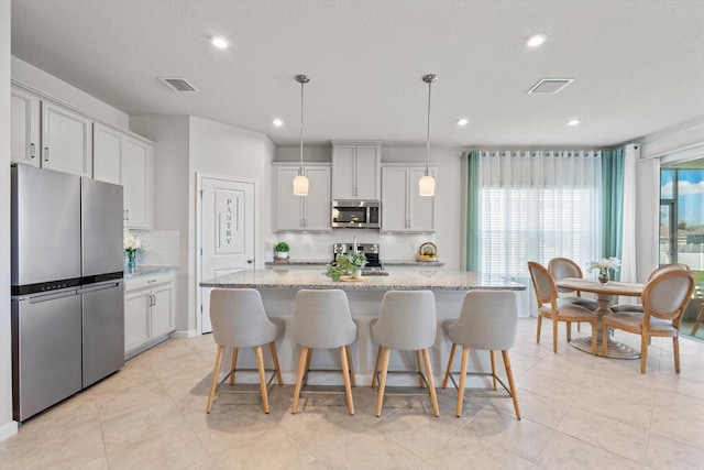 kitchen featuring light stone countertops, visible vents, stainless steel appliances, and backsplash