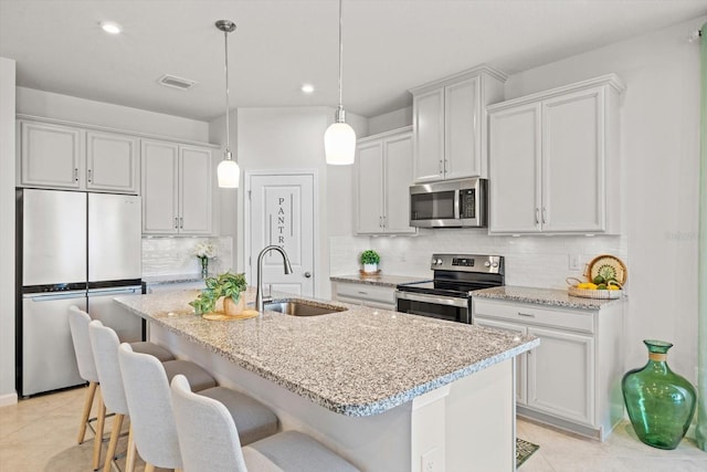 kitchen featuring tasteful backsplash, visible vents, appliances with stainless steel finishes, a kitchen breakfast bar, and a sink