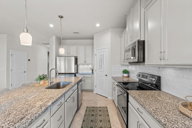 kitchen featuring hanging light fixtures, decorative backsplash, appliances with stainless steel finishes, a sink, and light stone countertops