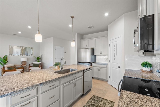 kitchen with appliances with stainless steel finishes, a sink, visible vents, and light stone countertops