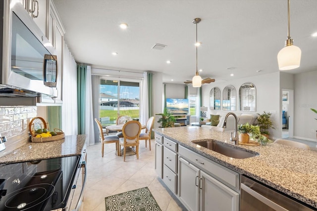 kitchen with stainless steel appliances, a sink, visible vents, open floor plan, and decorative light fixtures