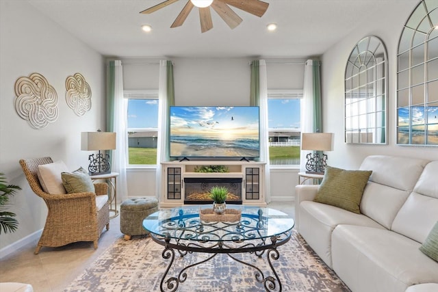 living area with recessed lighting, ceiling fan, a wealth of natural light, and a glass covered fireplace